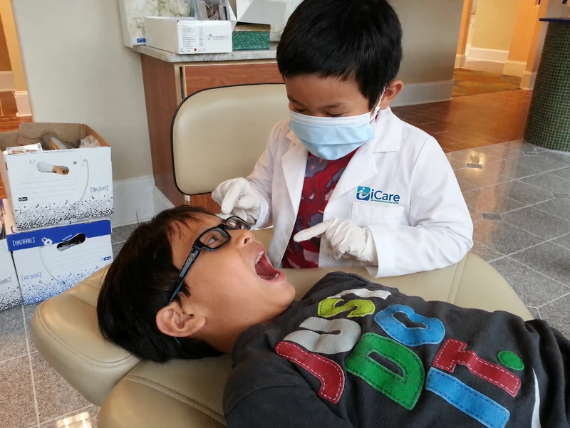Dr. Vinh Huynh's son and nephew playfully role-playing dentist and patient at iCare in Norcross, GA